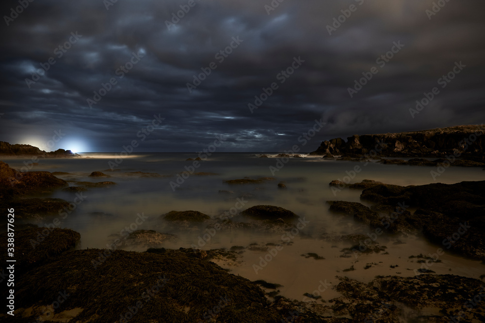 Obraz premium Landscape of rocks and cliffs in nature in the town of Noja made at night at low tide, Cantabria, Spain.