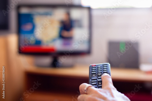 Closeup on tv remote control with hand of woman holding it. Changing television channels in living room. Schedule, choice variety concepts