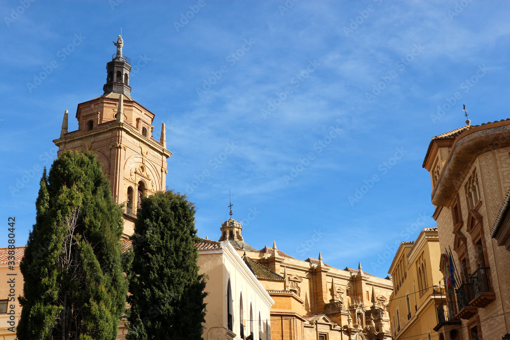 Bell tower of Guadix cathedral of the Incarnation, Granada, Spain surrounded by green trees