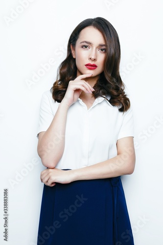 Young brunette woman with red lips and healthy clean skin, happy face with a smile. Beautiful woman in a white shirt and blue skirt posing in studio. 