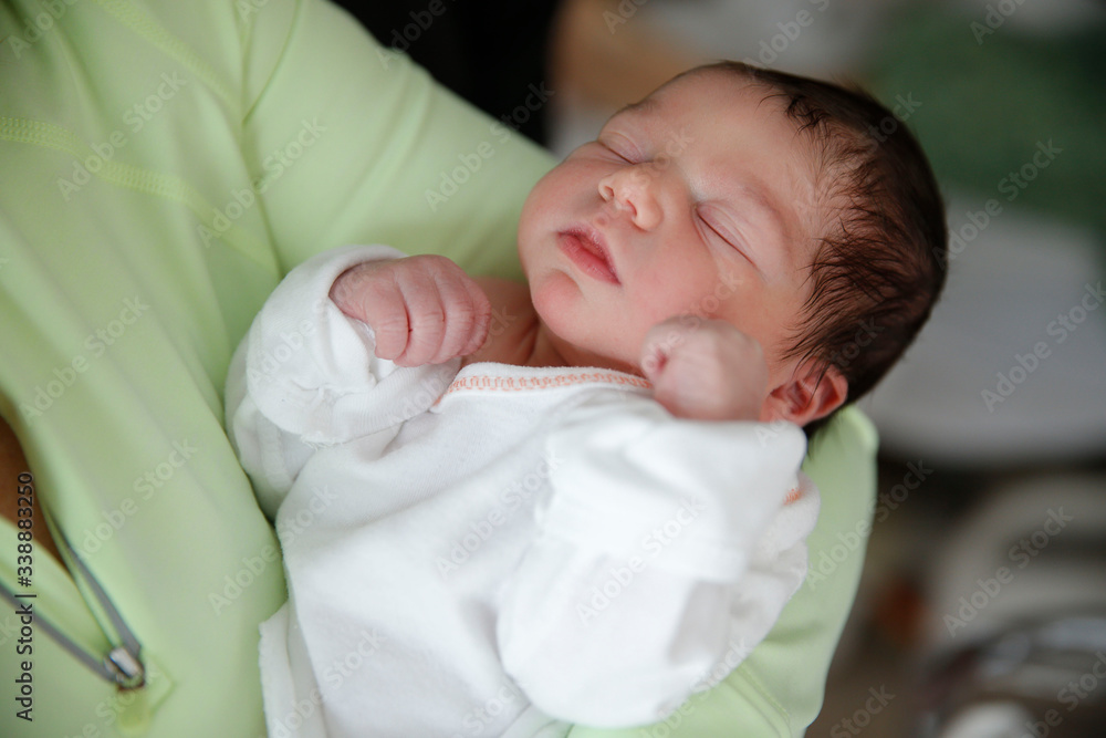 A newborn infant is held by her mother in the hospital A newborn infant is held by her mother in the hospital