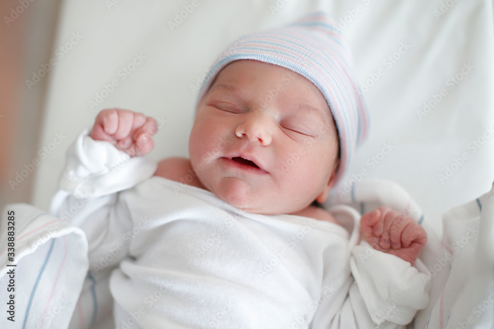 A newborn infant in diaper sleeps in her hospital bassinet A newborn infant in diaper sleeps in her hospital bassinet