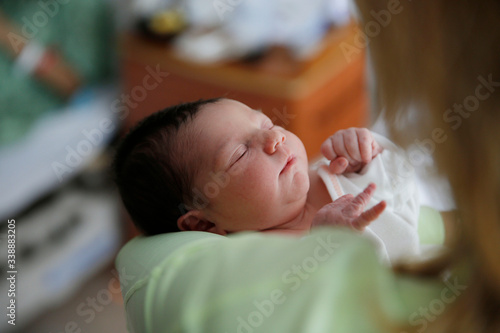 A newborn infant is held by her mother in the hospital