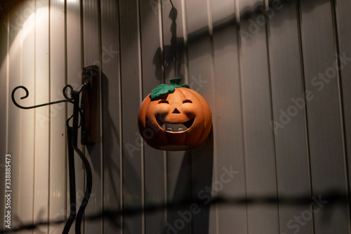 Ein Halloween Kürbis hängt an einer Kette an einer Wand und wird schlummerig angeleuchtet  photo