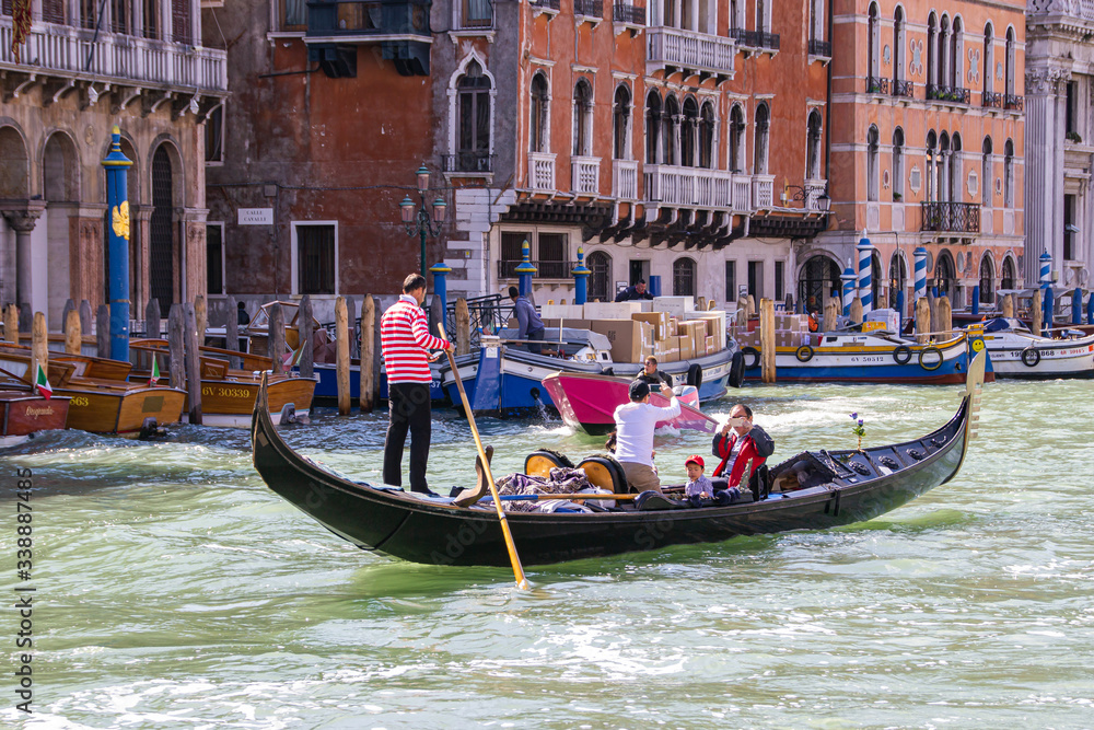 Water channels of Venice city. Gondolier rolls tourists on the gondola on Grand Canal in Venice, Italy.