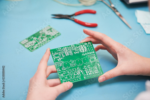 Microcontroller circuit board manufacture. Technician's hand with pcb photo