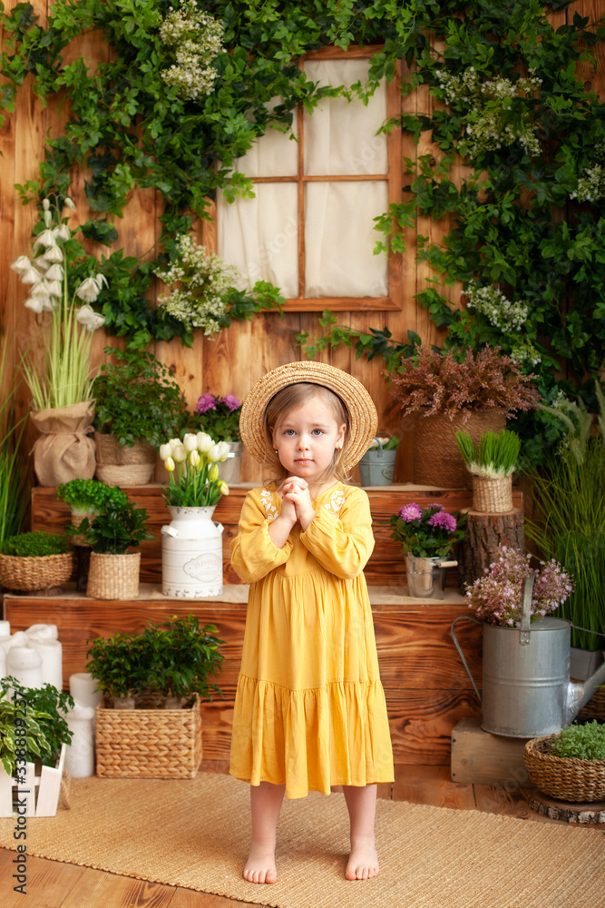 Child praying. Little girl hand praying, Hands folded in prayer concept for faith, spirituality and religion. A little girl is worth in backyard of wooden house, around green houseplants and flowers. 