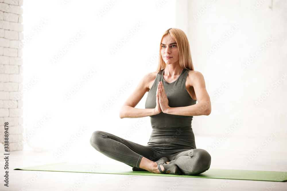 Fototapeta premium Yoga meditation at home. Beautiful young woman working out