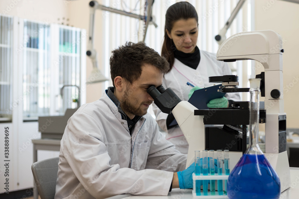 Microchemists Workflow of two chemists in the laboratory. The senior chemist examines ...