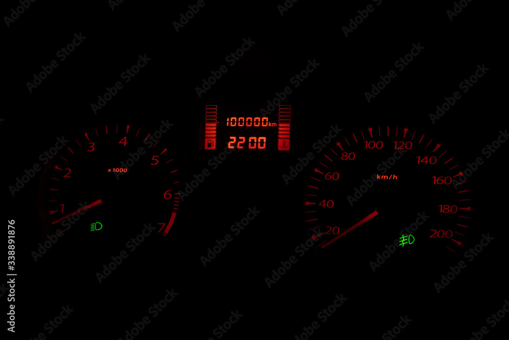 Black automobile dashboard with orange lights of odometer and green headlights symbols Selective focus Black automobile dashboard with orange lights of odometer and green headlights symbols Selective focus