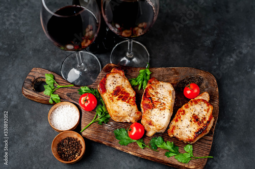 Dinner for two  grilled pork steaks with spices  glasses with red  wine on stone background