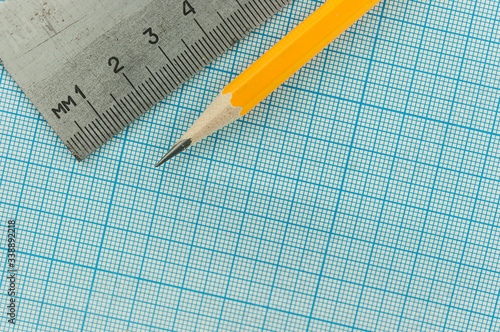 drawing compass, pencil, and ruler on graph paper background