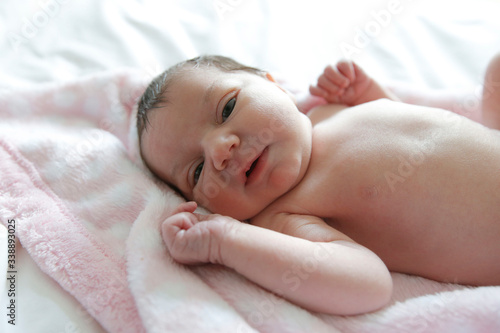 A newborn baby lays on a white bed