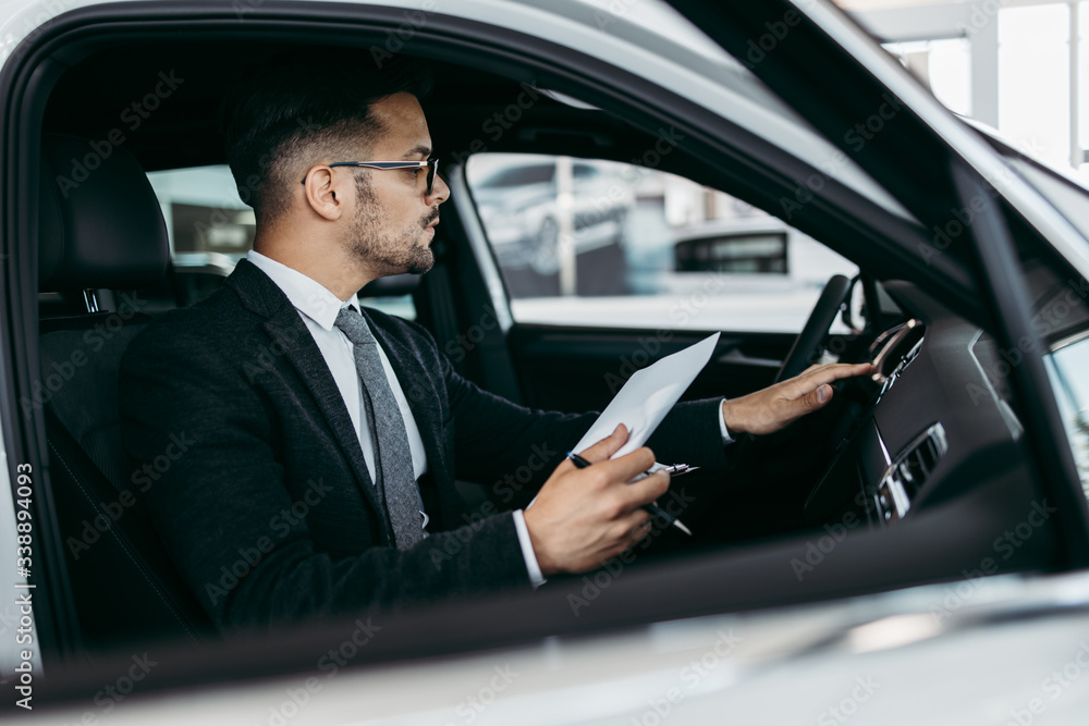 Car seller working in showroom and quality control checking of car details for the last time before buyer comes. Car seller working in showroom and quality control checking of car details for the last time before buyer comes.
