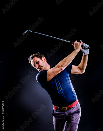 Close-up of a golf player intent on perfecting the swing isolated on dark background, vertical image
