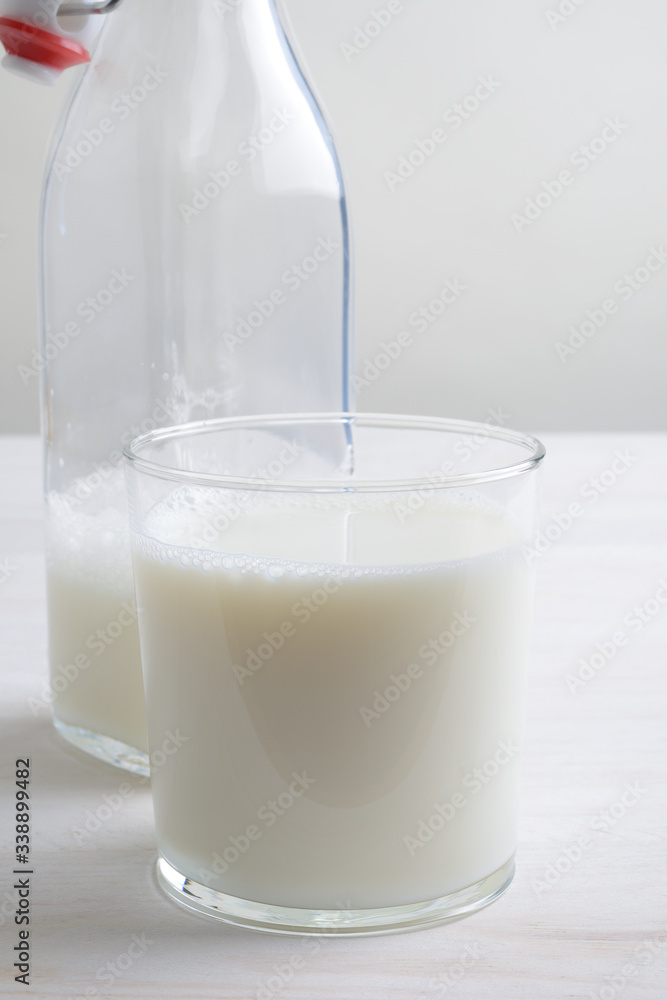 Vaso de leche y botella con tapón en la mesa blanca Vaso de leche y botella con tapón en la mesa blanca