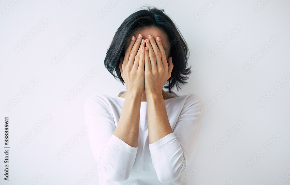 Stressed out. Young brunette woman with a short haircut is hiding her face while crying because of stress and anxiety. Stressed out. Young brunette woman with a short haircut is hiding her face while crying because of stress and anxiety.