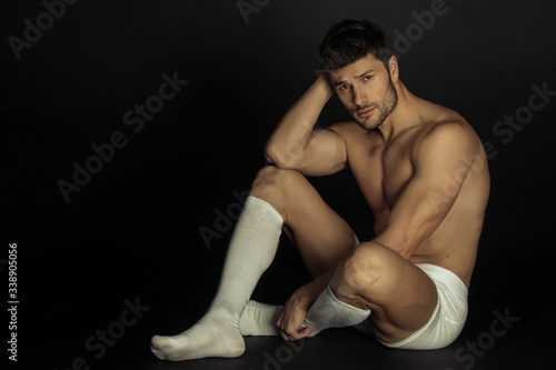 Strong stripped muscle male model in white underwear and white socks  on black isolated background
