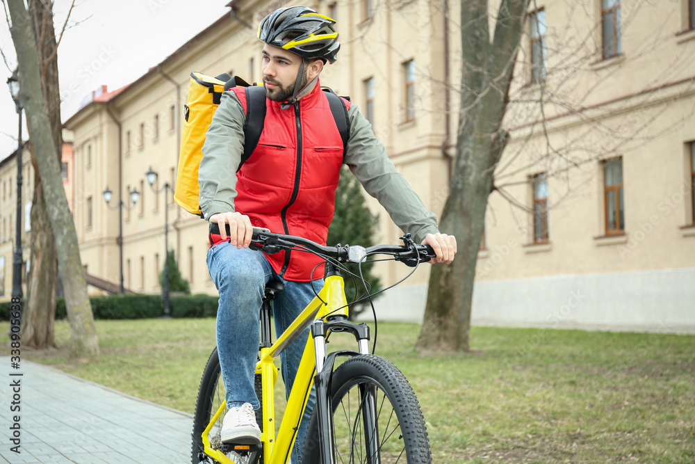 Courier with thermo bag riding bicycle outdoors. Food delivery service