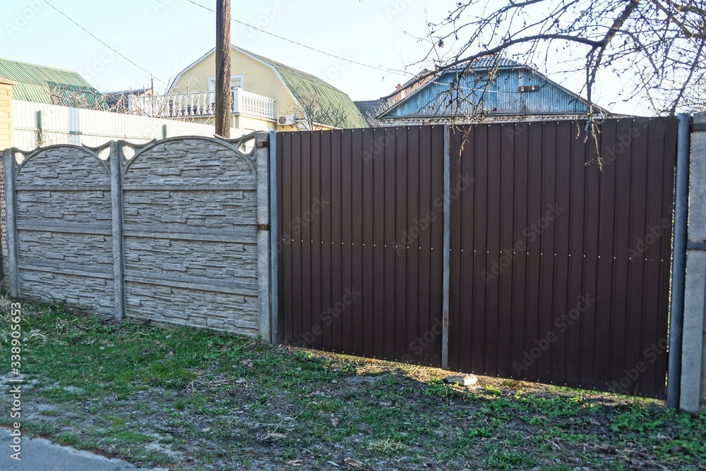Obraz premium big brown metal gate and fence on a rural street