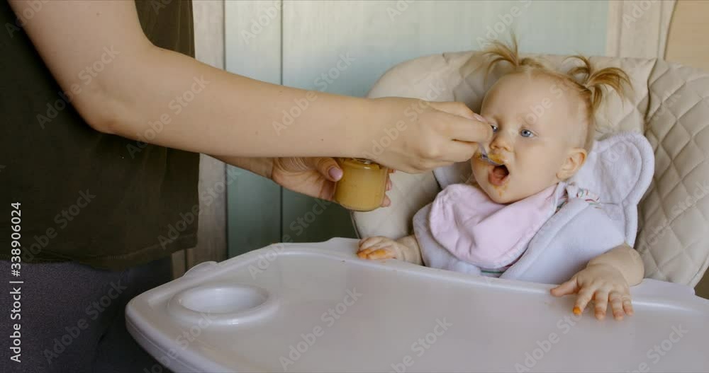 Caucasian mother feeding baby with spoon. RAW Graded footage 4K slow motion 60fps Caucasian mother feeding baby with spoon. RAW Graded footage 4K slow motion 60fps