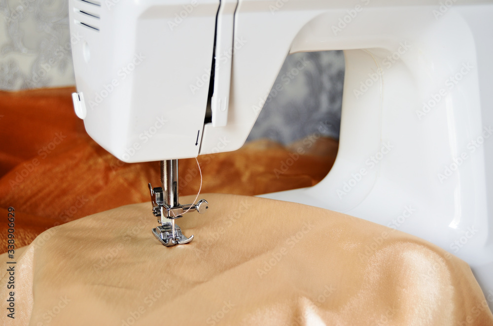 white sewing machine sews beige fabric