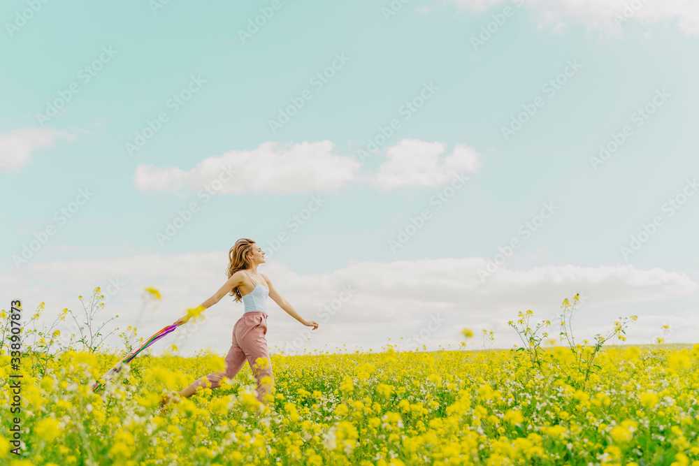 Young woman with colourful ribbons in a flower meadow in spring Young woman with colourful ribbons in a flower meadow in spring