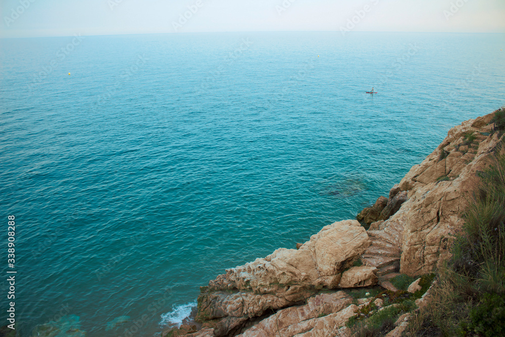 The prominent horizon of the Mediterranean Sea with a rocky shore. On the rock there are steps going down to the water itself.