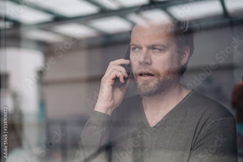 Portrait of businessman uon the phone behind windowpane photo