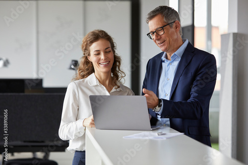 Smiling businessman and businesswoman working together on laptop in office