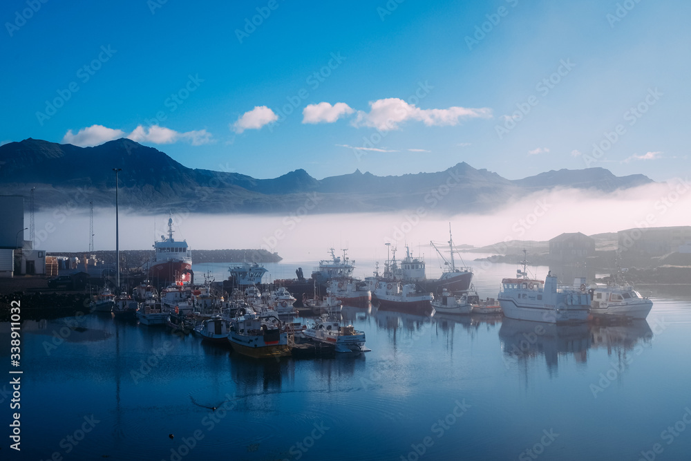 fishing boats on a pier in blue fog in an early sunny morning in the summer