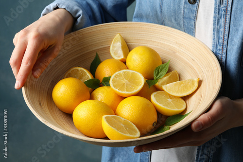 Woman holds bowl with lemons. Ripe fruit