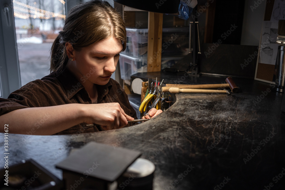 Female goldsmith working on her workbench in the workshop Female goldsmith working on her workbench in the workshop