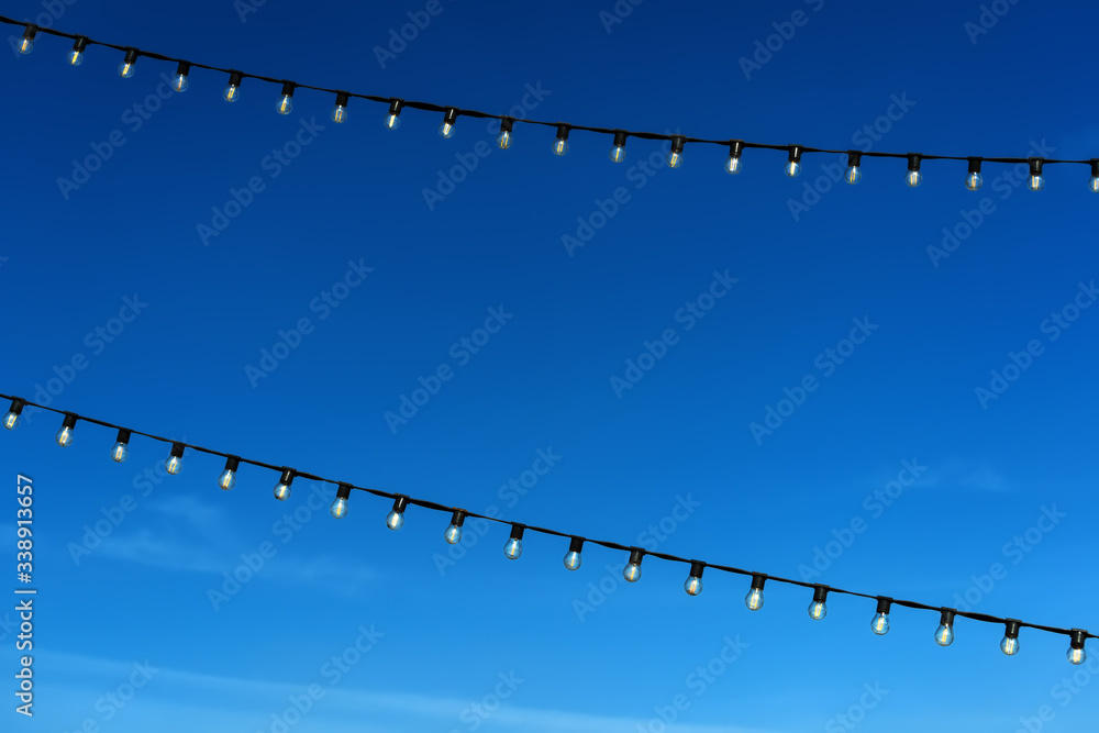 Two garlands of filament lamps with a dark blue sky background