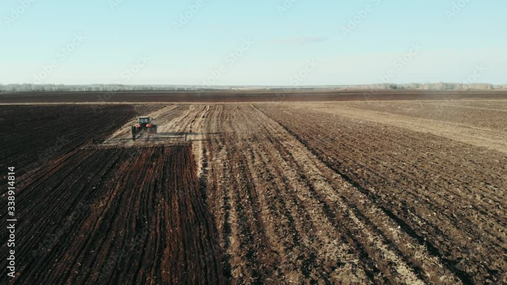Aerial view of Tractor plows the field in sunset, sunrise, raising dust, and behind it fly birds. Agriculture industry, cultivation of land. Food industry concept. Aerial view of Tractor plows the field in sunset, sunrise, raising dust, and behind it fly birds. Agriculture industry, cultivation of land. Food industry concept.
