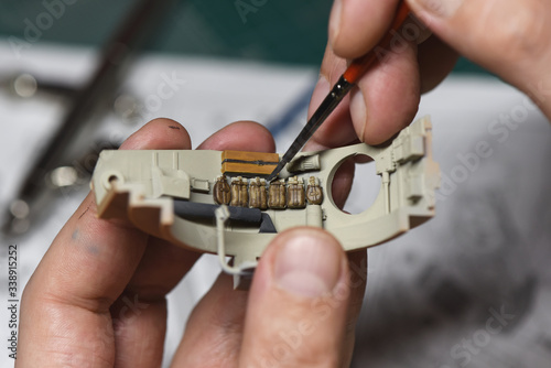 Plastic Modeling and model building. Close up of male hands painting and assembling scale model of a tank. Hobby and leisure at home. Hobbies in quarantine. Modelism macro shot. 