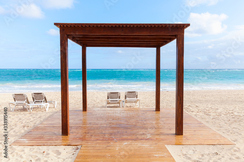 Empty wooden gazebo and sun loungers on a beach