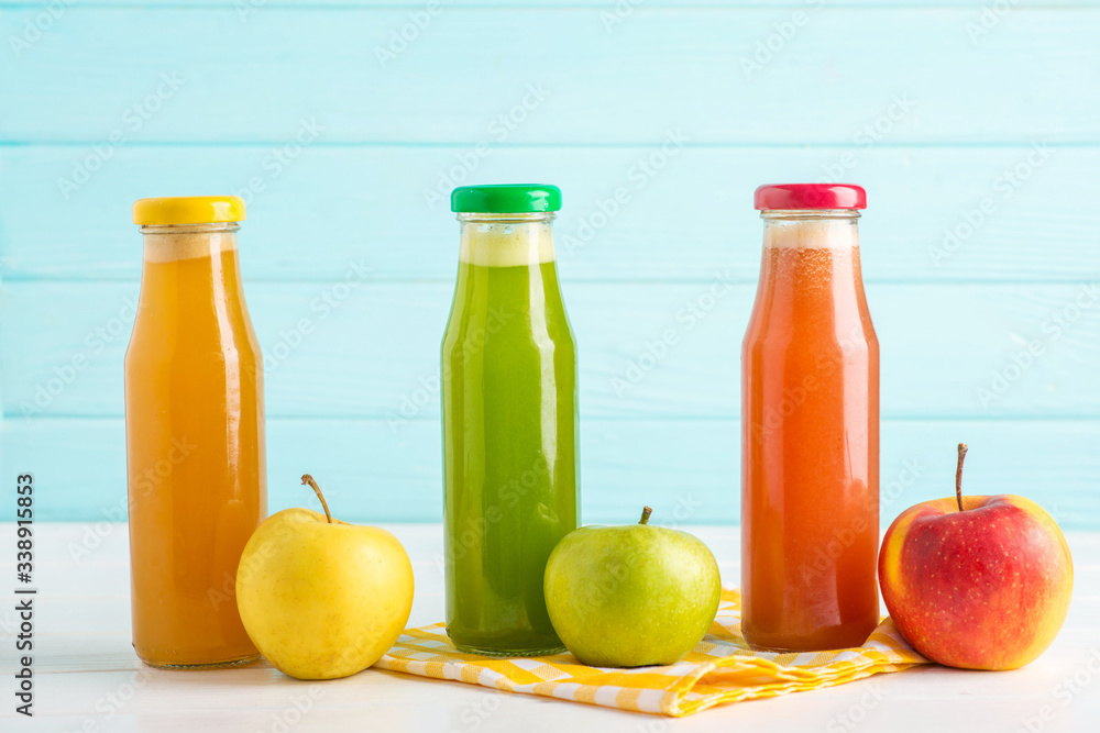 fresh apple juices from red, yellow, green apple on a white table fresh apple juices from red, yellow, green apple on a white table