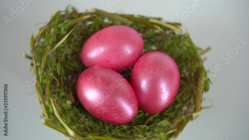 COLORED EGGS FOR EASTER. GOLDEN EGGS IN THE NEST ON THE WHITE BACKGROUND