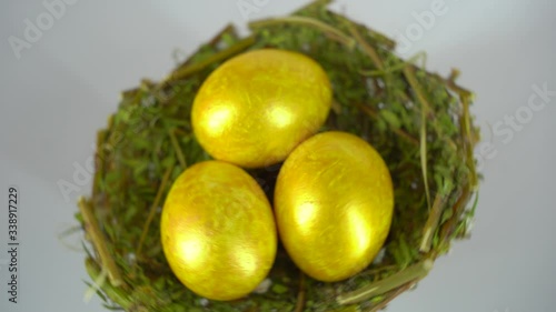 COLORED EGGS FOR EASTER. GOLDEN EGGS IN THE NEST ON THE WHITE BACKGROUND