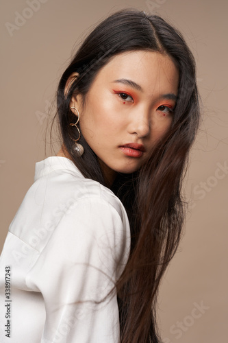 Beautiful woman of Asian appearance bright makeup charm beige background