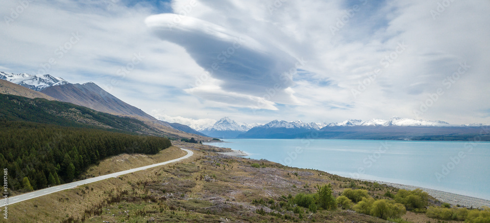 Alpine vista with turquoise lake and mountains in backdrop with highway leading towards them, shot at Aoraki/Mt Cook National Park, New Zealand