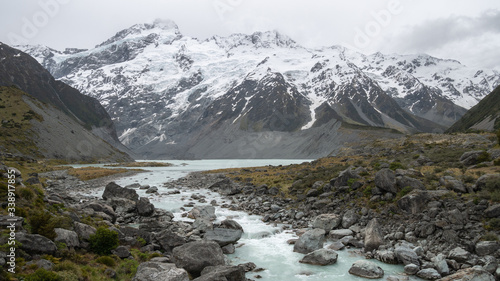Glacier stream flowing from lake under majestic snowy mountain, landscape scene shot at Aoraki/Mt Cook National Park, New Zealand