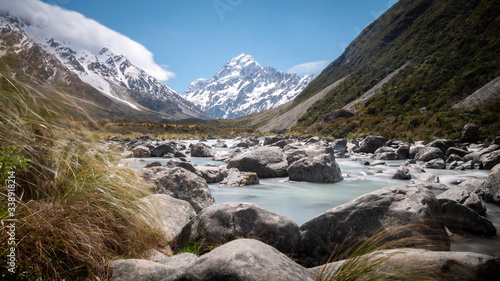 Panoramic long shutter speed shot of alpine valley with impressive peak on its end (Mt Cook) with glacial river used as leading line. Shot in Aoraki / Mt Cook National Park, New Zealand