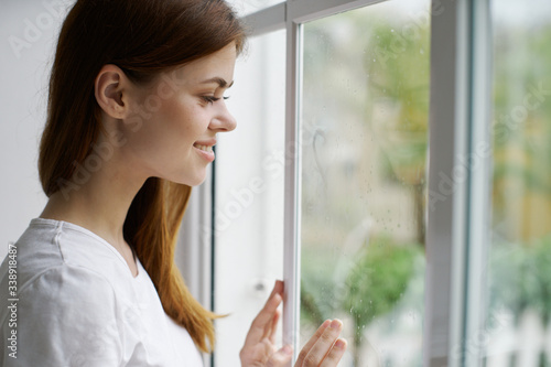 A cheerful woman looks out the window with a pensive interior view