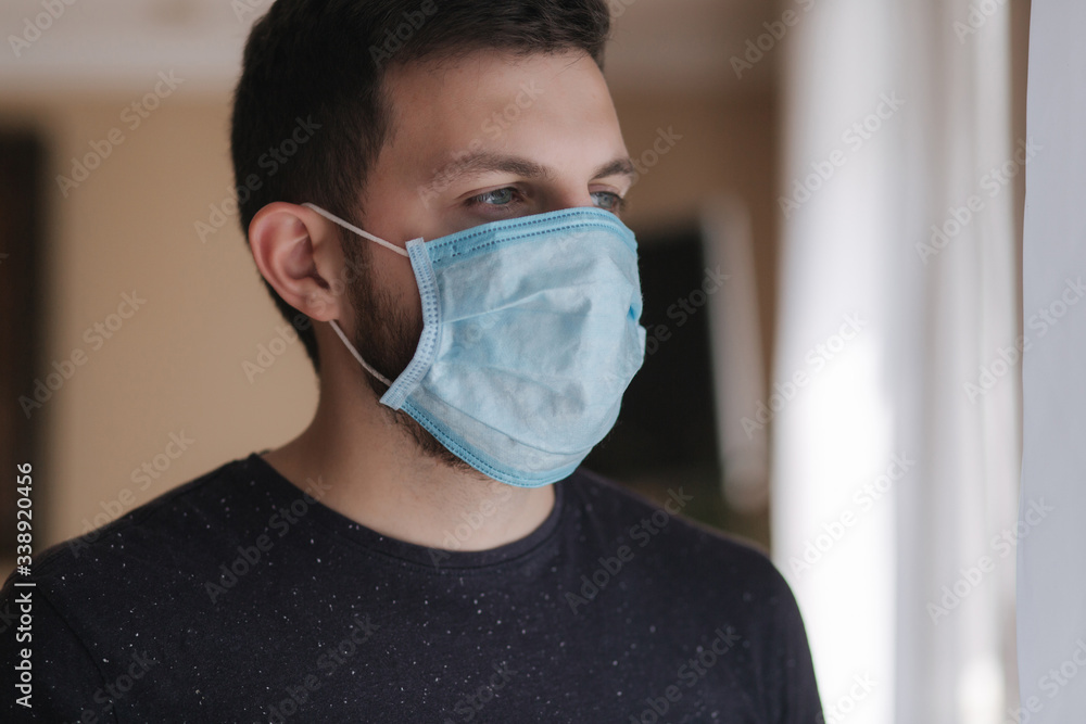 Man put on madical mask at home. Young man in protective mask. Coronavirus theme Man put on madical mask at home. Young man in protective mask. Coronavirus theme