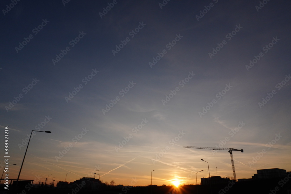 amazing sky at sunset with small clouds and a trace of the plane or contrail in the city against the background of houses and the Church. the sun's rays are visible through the clouds.