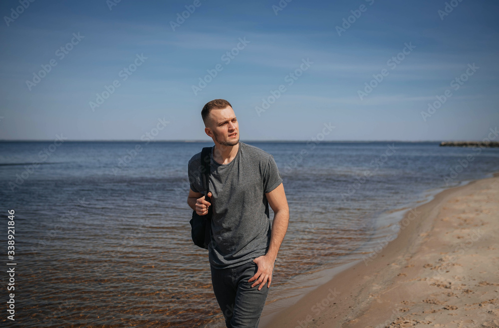 Young guy with a backpack on a sandy wild beach Young guy with a backpack on a sandy wild beach
