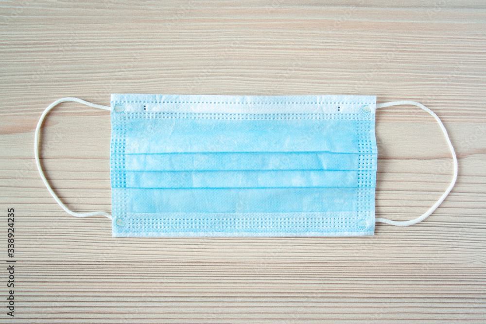 Disposable medical mask on wooden backggroun against bacteria and viruses. Stop the spread of coronavirus, self-defense. Copy space Disposable medical mask on wooden backggroun against bacteria and viruses. Stop the spread of coronavirus, self-defense. Copy space