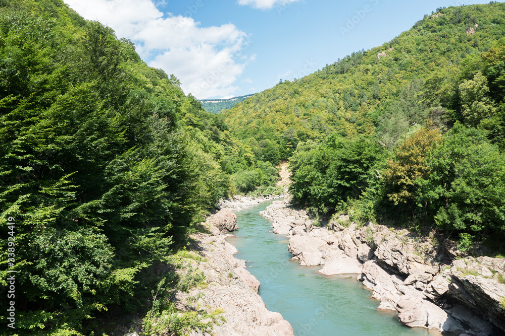 picturesque view of blue river surrounded by rocks in beautiful  green mountains, summer, blue sky, traveling in scenic places 
